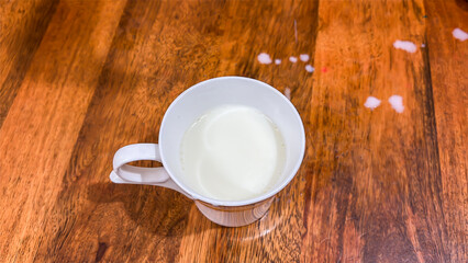 cup of fresh milk on wooden table top view