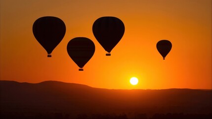 Fototapeta premium Five colorful hot air balloons float at varying heights against a vibrant orange sunset,