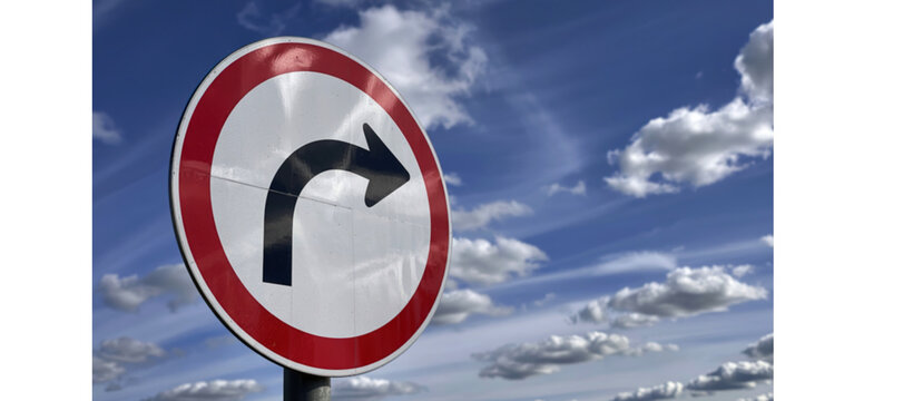 A roundabout traffic sign against a cloudy blue sky