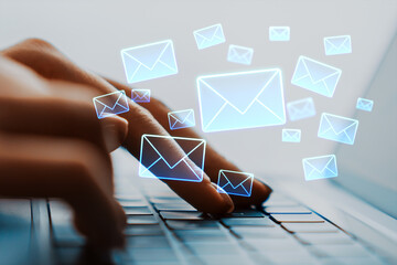 Person typing on laptop keyboard with glowing email icons floating above representing digital communication and online messaging concept.