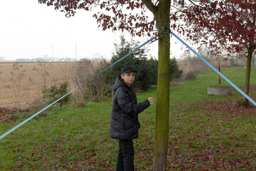 Child by tree, Young boy leaning against mosscovered tree amidst suburban scenery, Child calmly...