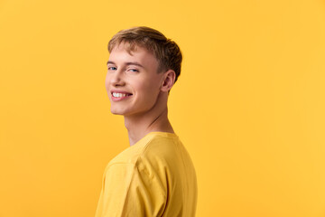 Obraz premium Man smiling in a yellow shirt against a yellow studio background, posed naturally for fashion and lifestyle stock, capturing bright mood, casual style and confident expression.