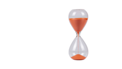 An hourglass with orange sand in a clear glass container, positioned vertically, indicating the passage of time no background
