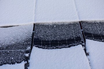 Snow covered solar panels in winter reducing energy output efficiency