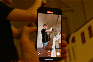 smartphone photographing couple on staircase, intimate embrace, soft warm light, retro banister, documentary feel, photographer framing from behind, affectionate mood, candid lifestyle scene