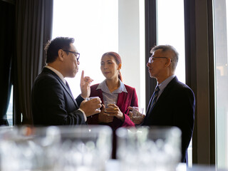 Group of business professionals engaged in serious conversation during a corporate event, showing effective workplace communication, leadership, and idea sharing in a modern setting