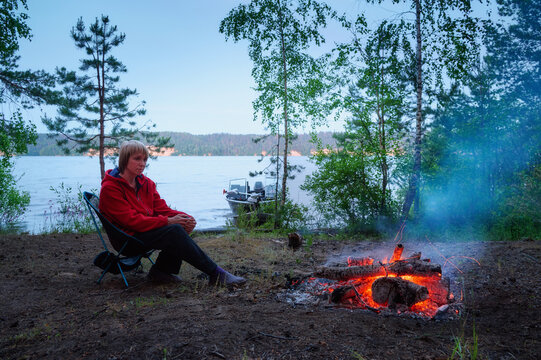 A woman at a campfire on the riverbank evening.