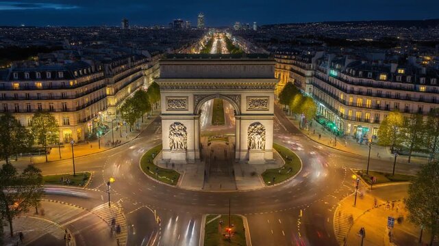 Nighttime view of Arc de Triomphe in central Paris, illuminated by street lights and urban glow.