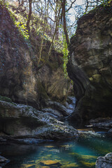 Sychryd Gorge with towering rock walls framing a turquoise stream of river Afon Sychryd flowing through scattered boulders in Vale of Neath, south Wales