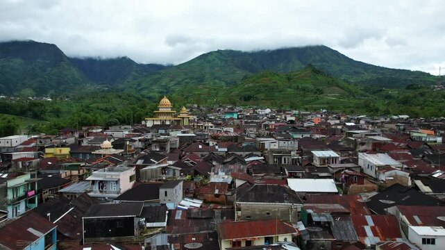 Close up aerial drone footage of an indonesia mountain local village located on a cliff, with a mosque in the middle, on the slope of Dieng plateau volcanic area, in Java island