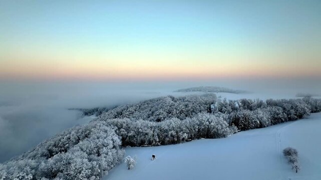 Aerial winter sunrise view of the Irchel with snow fog and the Irchelturm