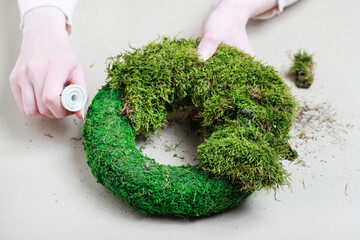 Florist at work: woman shows how to make classic moss wreath. Step by step, tutorial.
