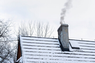 Nasty black smoke from burning garbage in the home furnace comes out of the house's chimney.
