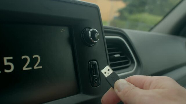 white hand plugging audio cable into car stereo USB port, adjusting volume knob and screen display, handson setup for music playback during roadtrip, modern infotainment.