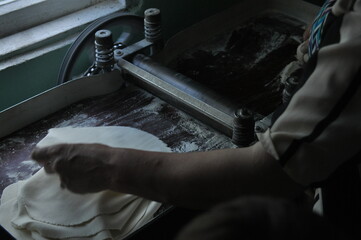 Hand rolling dough in a small kitchen during afternoon hours for traditional bread preparation