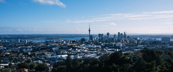 Panoramic view of Auckland city skyline featuring Sky Tower and Waitemata Harbour under a clear blue sky © 愚生 覃