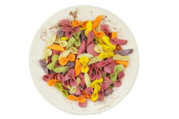 Farfalle on ceramic plate isolated on white background. Top view. Uncooked pasta of different colors.