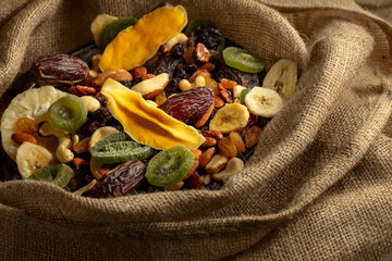 Dried tropical fruits and nuts in burlap bag.