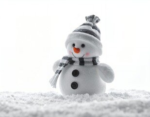 Adorable snowman toy with striped hat and scarf standing in fresh white snow.