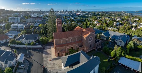 Fototapeta premium Aerial view of a church in Remuera, Auckland, New Zealand, with the city skyline in the background. The photo showcases the architecture and urban landscape.