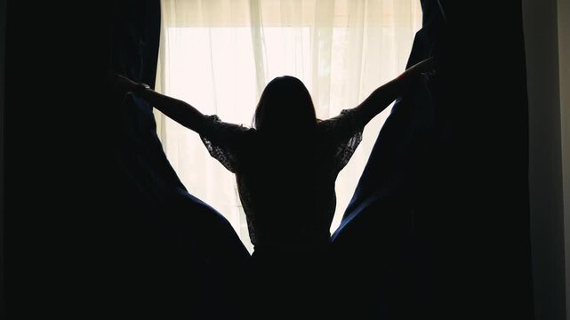 The woman pulls back the curtains and opens the morning light inside. High quality 4k footage