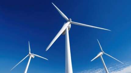 Three large white wind turbines stand tall with their blades rotating gracefully against a clear blue sky,