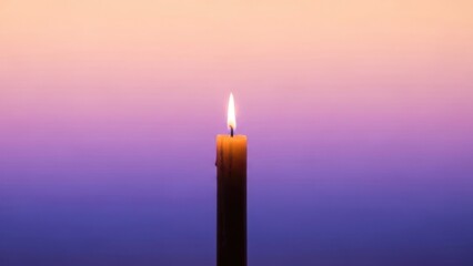 Fototapeta premium A single glowing candle flame illuminates a serene gradient background of warm peach and deep