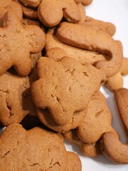 A plateful of freshly baked gingerbread cookies in multiple shapes, featuring a rich brown color and light cracks. Ideal for holiday gatherings, family baking, and cozy festive moments.