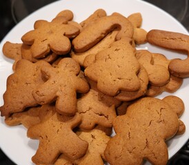 A plate full of homemade gingerbread cookies in fun shapes, baked to a golden brown. Perfect holiday treat for family gatherings, parties, and cozy moments at home with friends.