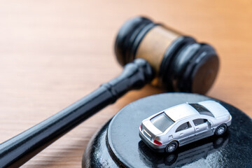 A judge gavel and a miniature car on a wooden table. Car auction, vehicle law, insurance claims, traffic regulations concept.