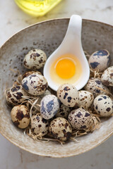 Close-up of fresh uncooked quail eggs in a beige bowl, vertical shot, selective focus