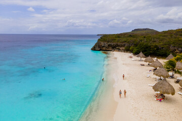 Obraz premium Visitors bask in the warm sun at Cas Abao Beach in Curacao, enjoying the clear blue waters and sandy shores. The tropical setting invites relaxation and fun in a picturesque Caribbean paradise.