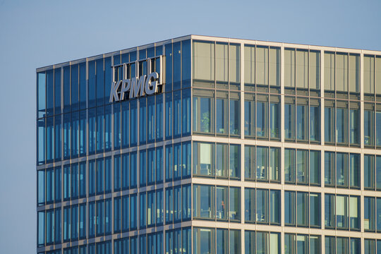 Modern glass office building with KPMG logo reflecting the sky in its facade