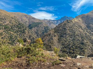 Rugged mountain slopes descend into a deep valley beneath the towering La Alcazaba and Mulhac&eacute;n peaks. This panoramic view showcases the vastness of Vereda de la Estrella in Sierra Nevada, Spain.
