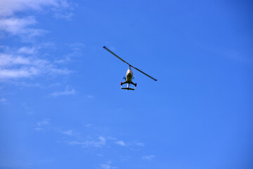 Gyrocopter flying with background of blue sky