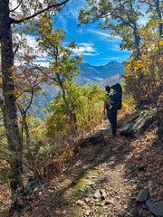 A man hiking with a child carrier treks through the forest on the Vereda de la Estrella trail facing high mountain views in the Sierra Nevada National Park, Andalusia, Southern Spain.