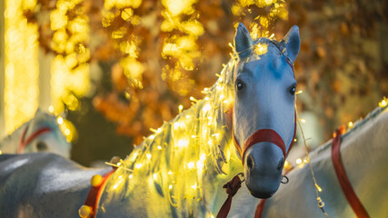 White horse statue decorated with glowing string lights at autumn park