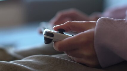 Child's hands holding a wireless game controller while playing a video game. Close-up. Gaming lifestyle and after-school entertainment. Child playing a video game.