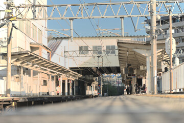 Fototapeta premium 青空の下に広がる日本の地方都市の鉄道駅のホームと架線、静かな昼下がりの駅構内の風景素材