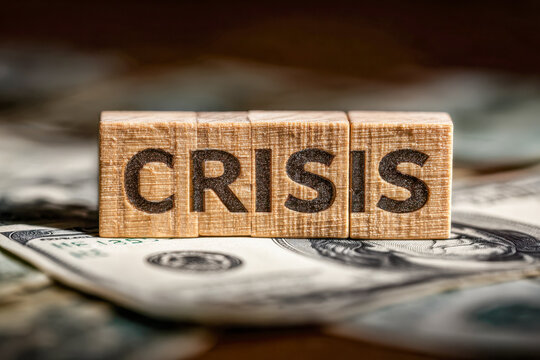 Wooden blocks spelling crisis placed on scattered us dollar bills symbolizing financial instability and economic challenges in uncertain times - Powered by Adobe