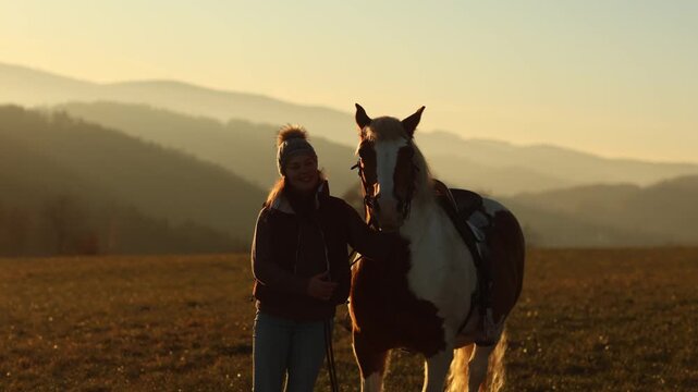 Young woman gently cuddling and interacting with her pinto Haflinger mix mare, emotional bond and trust at sunset