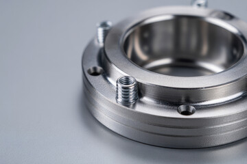 Precision-machined metallic flange component featuring threaded studs and smooth surface finish captured on a neutral gray background for industrial applications