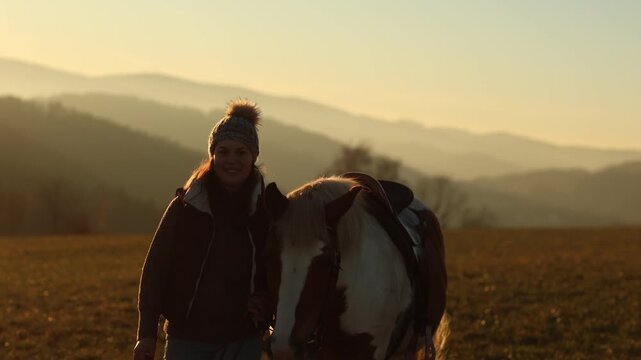 Young woman gently cuddling and interacting with her pinto Haflinger mix mare, emotional bond and trust at sunset