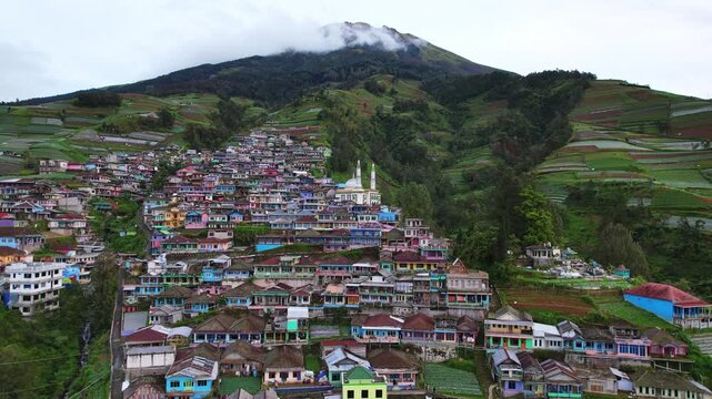 Aerial drone footage diving into the famous Nepal Van Java village, on the slope of Sumbing volcano, in Magelang area, Java island, Indonesia, in a white cloudy heavy atmosphere