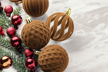 Christmas ball ornaments, brown velvet baubles, and pine branches on marble table background