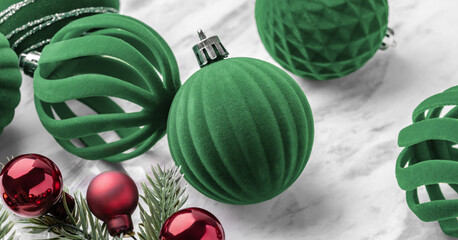 Green velvet baubles, Christmas ball ornaments and pine branches on marble table