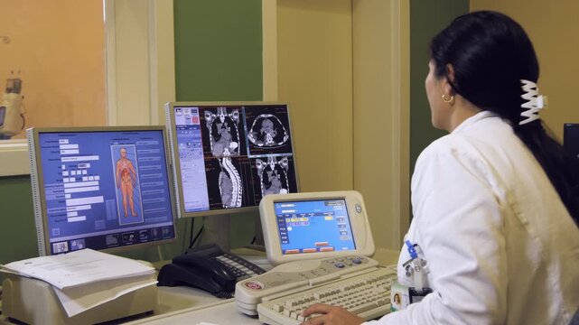 Radiology technician working on a computer with CT scan in hospital