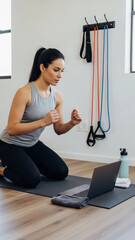 Woman exercises at home in front of a laptop while using a workout mat and resistance bands on wall