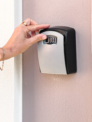 Hand inputting code on key lockbox for access