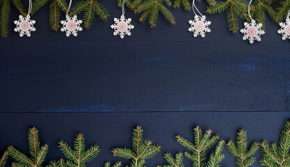 Wooden Christmas background with fir branches and snowflakes on blue background